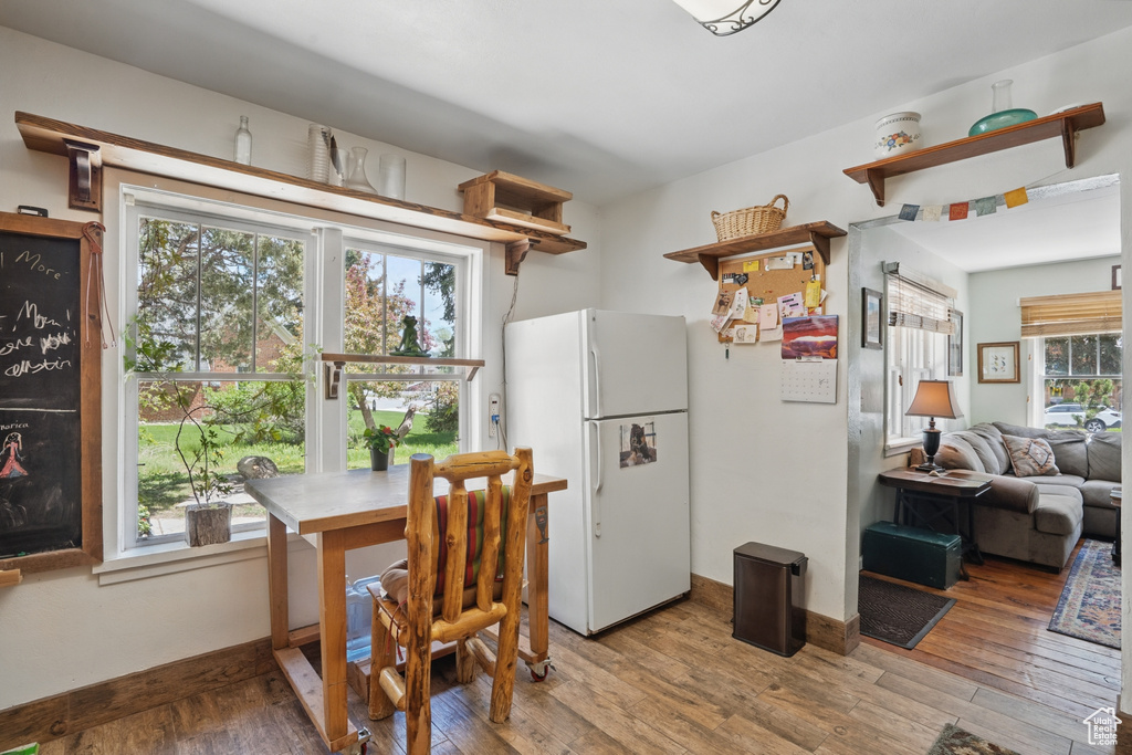 Kitchen with freestanding refrigerator, open shelves, wood-type flooring, and baseboards