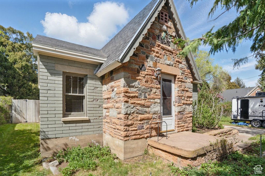 View of side of home featuring fence and roof with shingles