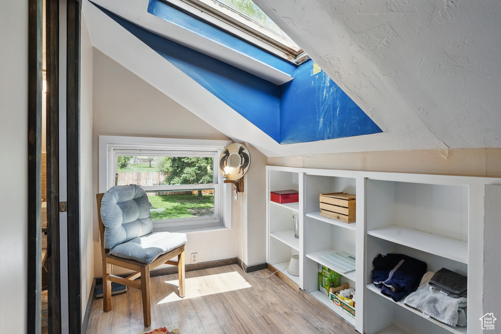 Sitting room featuring wood finished floors, baseboards, and lofted ceiling