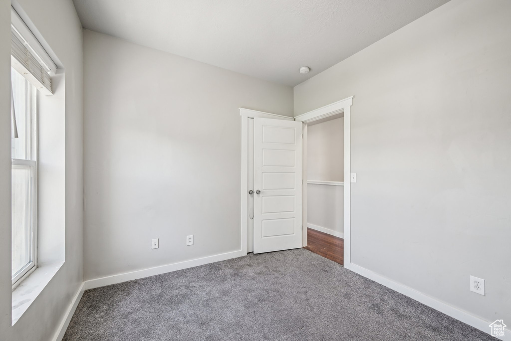 Carpeted spare room featuring baseboards and a smoke detector