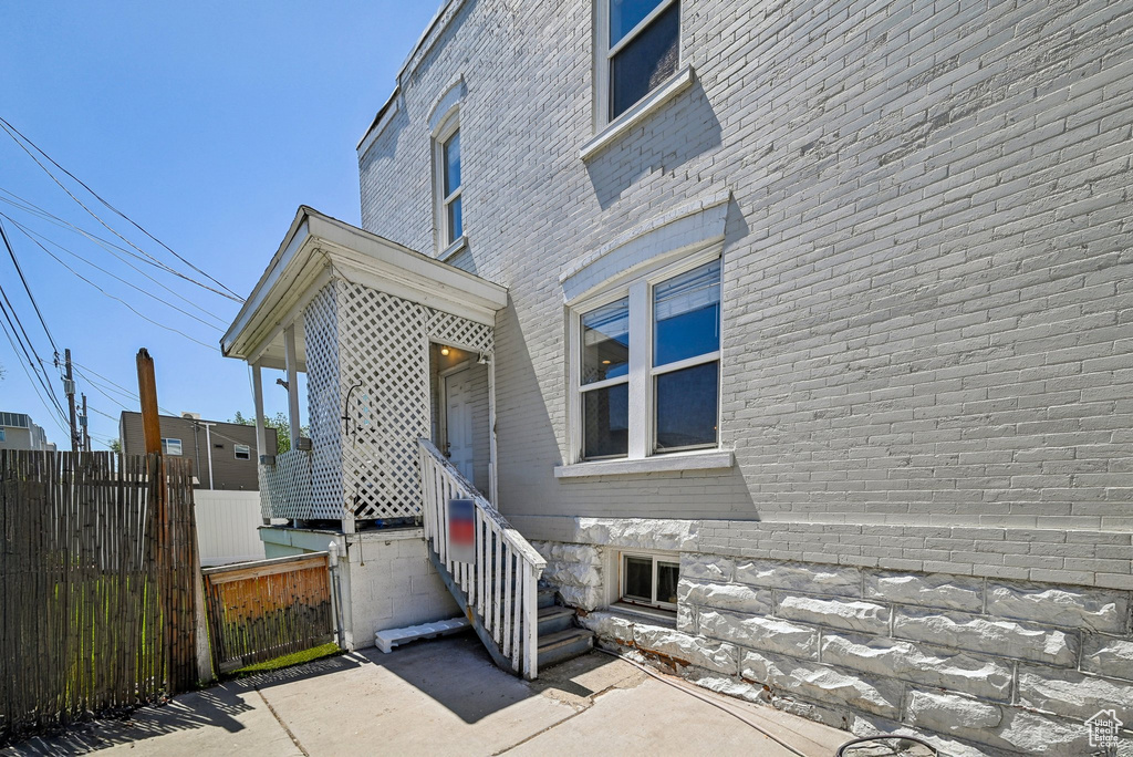 View of exterior entry with fence and brick siding