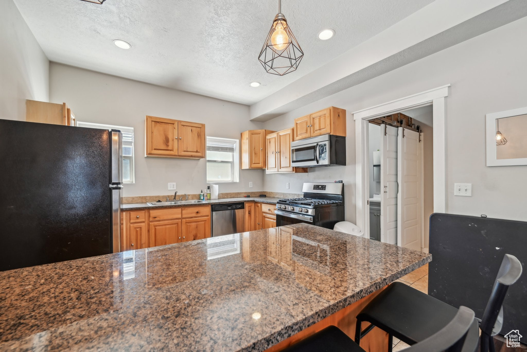 Kitchen with appliances with stainless steel finishes, a sink, a breakfast bar, recessed lighting, and a peninsula
