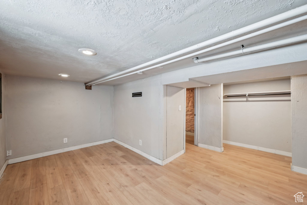 Finished basement with wood finished floors, baseboards, a textured ceiling, and recessed lighting