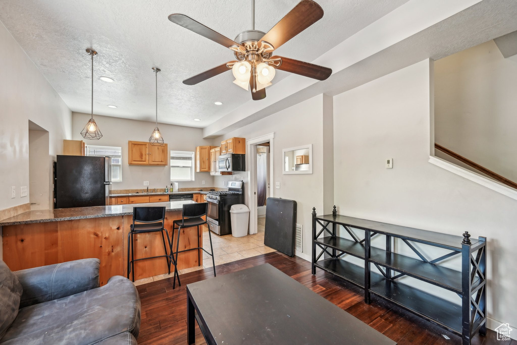 Living room with a textured ceiling, wood finished floors, a ceiling fan, baseboards, and recessed lighting