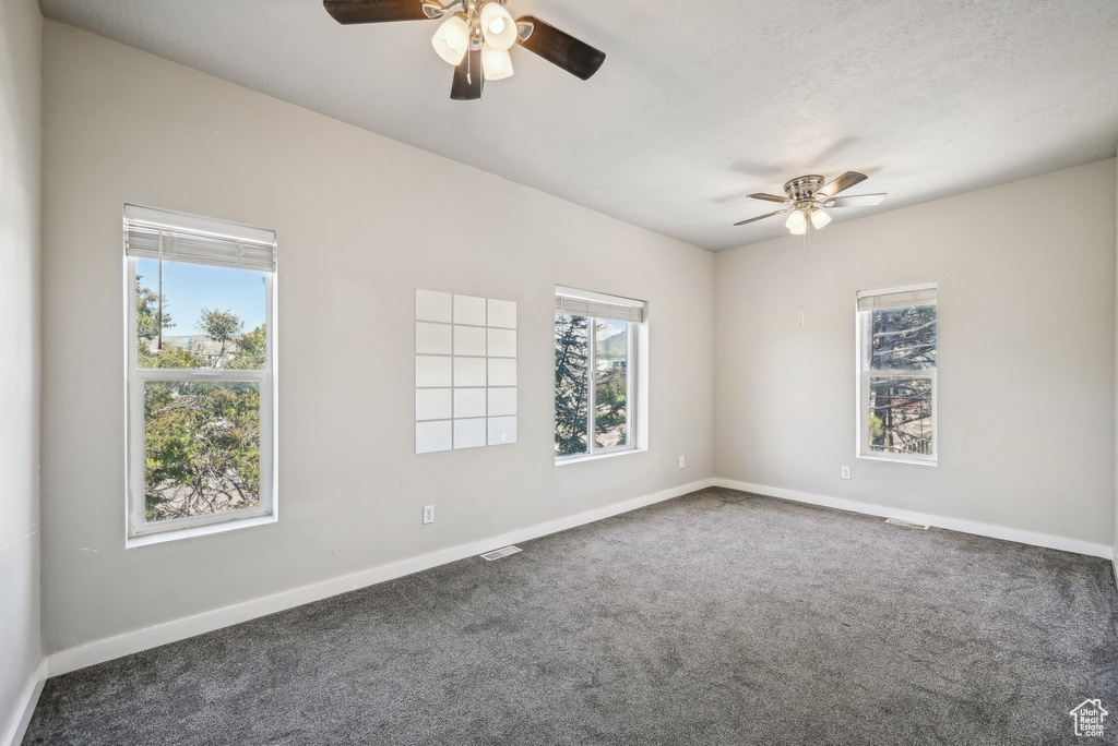 Spare room with a ceiling fan, carpet flooring, and baseboards