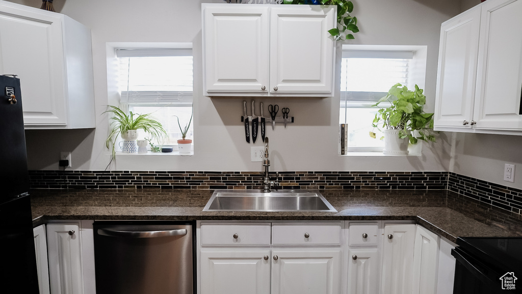Kitchen featuring dishwasher, a sink, dark countertops, and white cabinets
