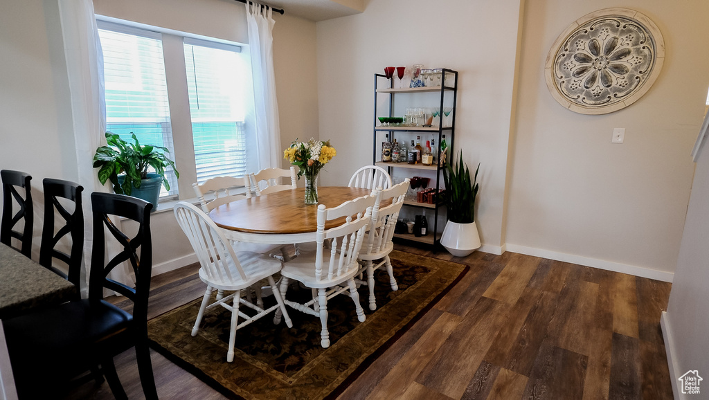 Dining area with dark wood-style flooring and baseboards
