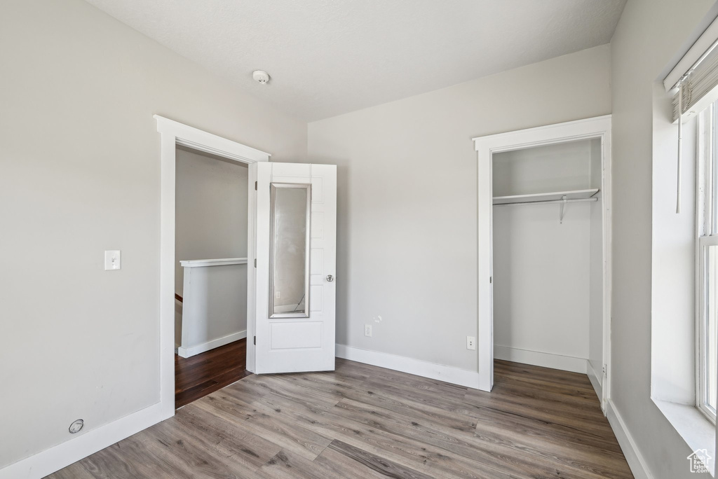 Unfurnished bedroom with wood finished floors, a closet, and baseboards