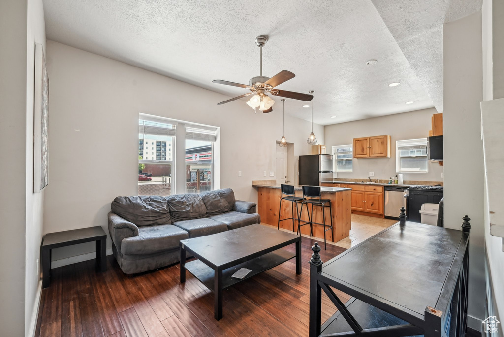 Living area with a textured ceiling, a ceiling fan, light wood-type flooring, recessed lighting, and baseboards