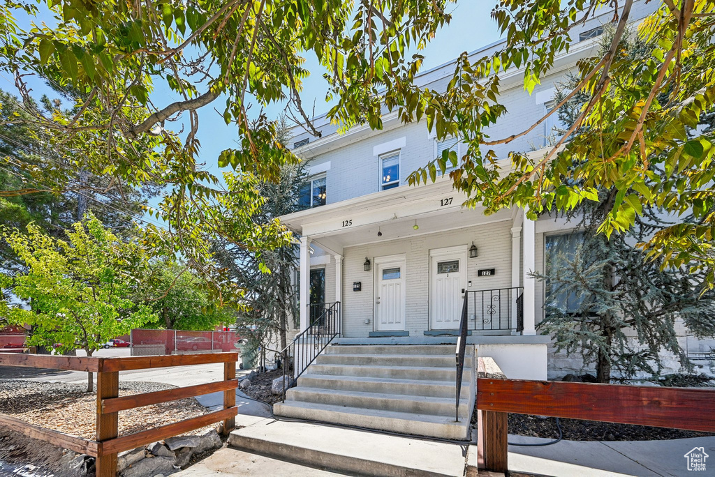 View of front of property featuring brick siding, a porch, and fence