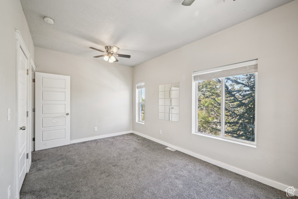 Carpeted spare room with ceiling fan, baseboards, and a smoke detector