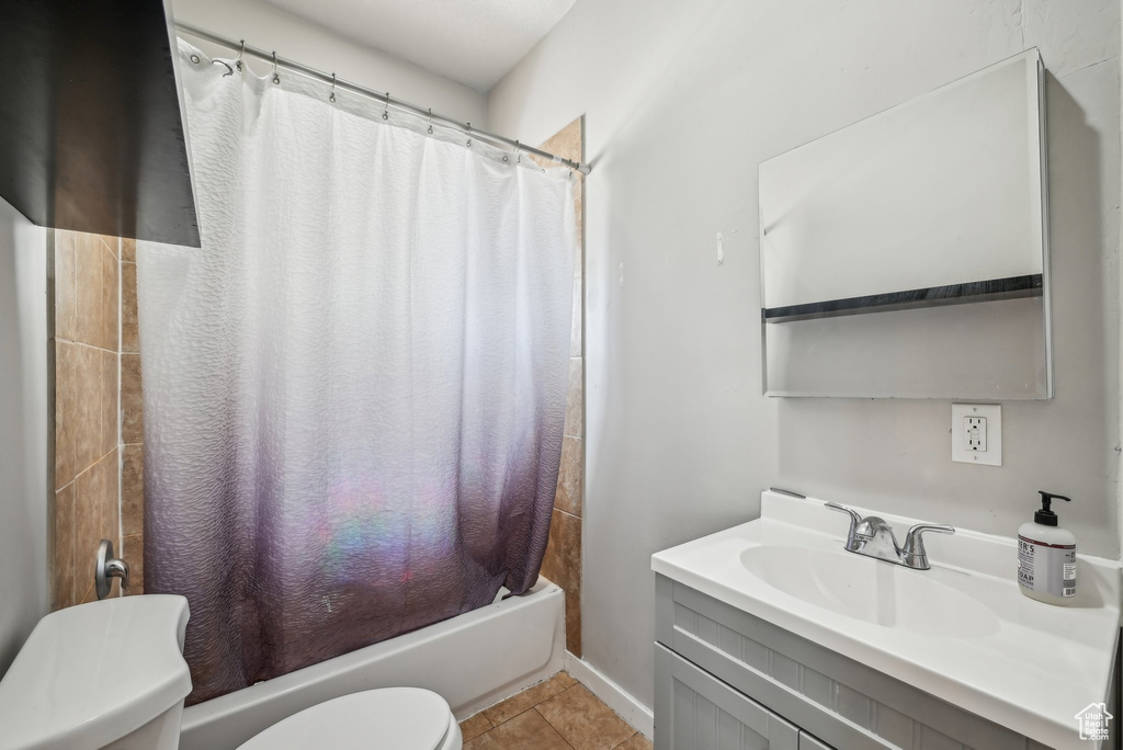 Full bathroom featuring toilet, shower / tub combo with curtain, vanity, and tile patterned floors