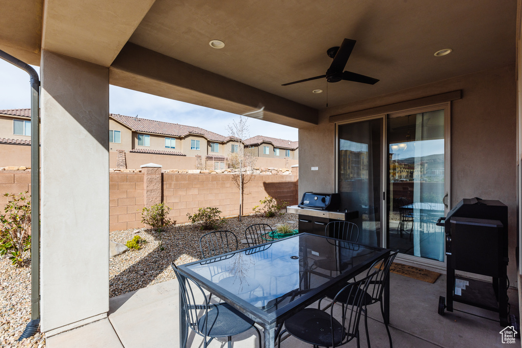 View of patio featuring a ceiling fan, fence, outdoor dining space, and a residential view