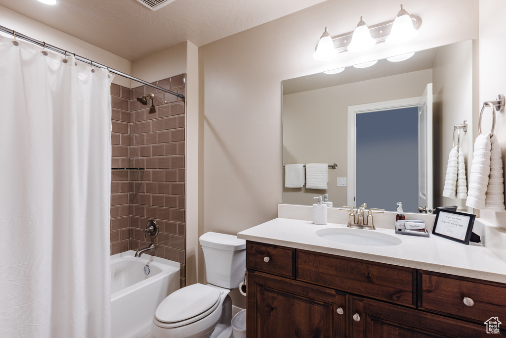 Bathroom featuring toilet, vanity, and shower / bath combination with curtain