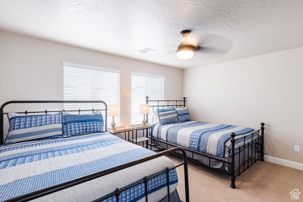 Bedroom featuring light colored carpet, a ceiling fan, and baseboards