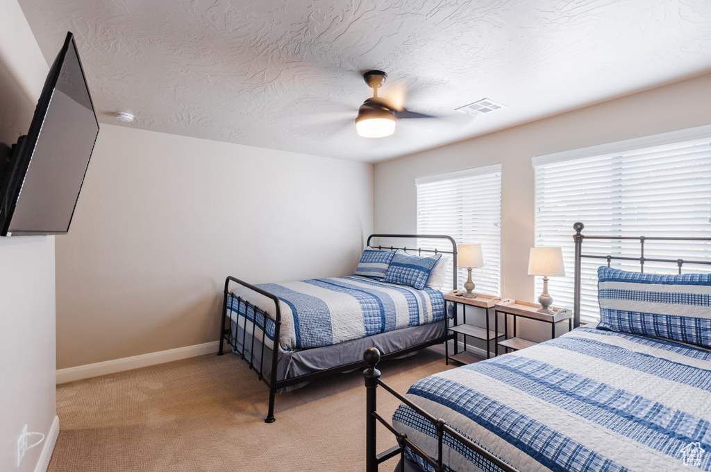 Bedroom featuring carpet floors, baseboards, a ceiling fan, and a textured ceiling