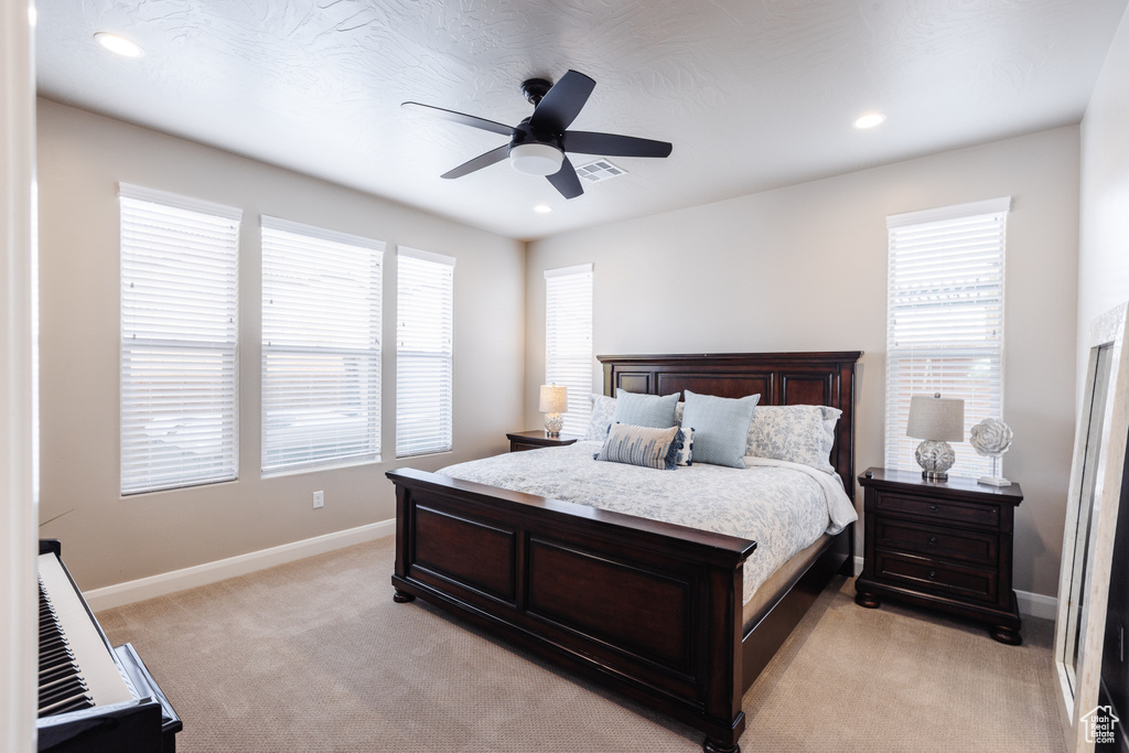 Bedroom featuring multiple windows, baseboards, light colored carpet, a ceiling fan, and recessed lighting