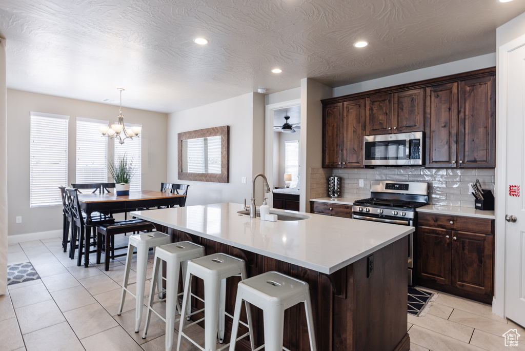 Kitchen with appliances with stainless steel finishes, a sink, tasteful backsplash, a breakfast bar, and an island with sink