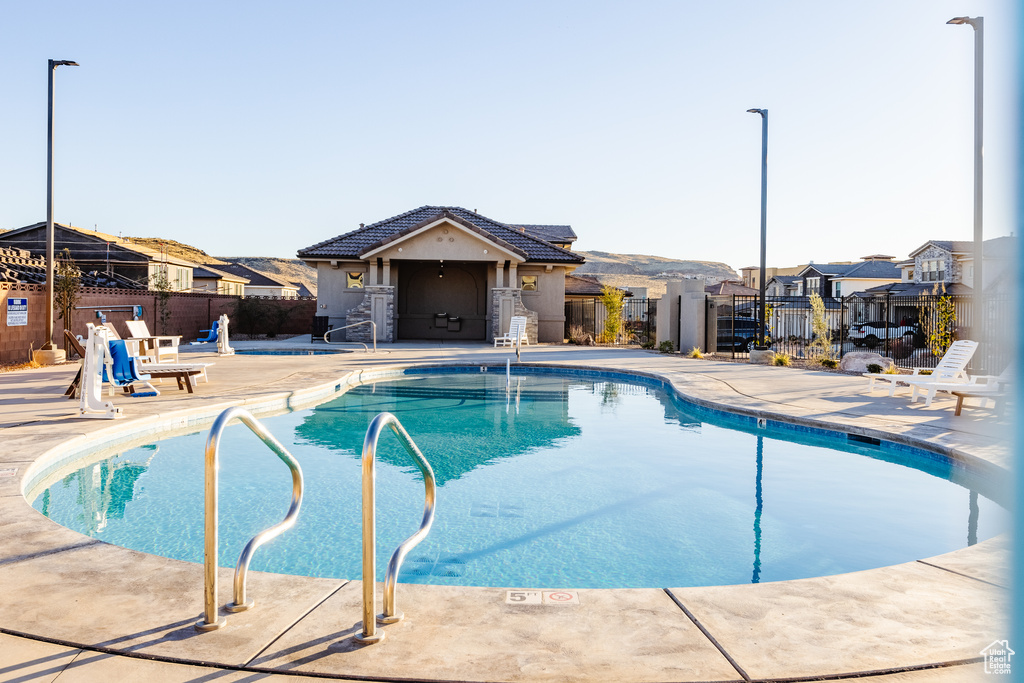 Community pool featuring fence, a patio area, and a residential view
