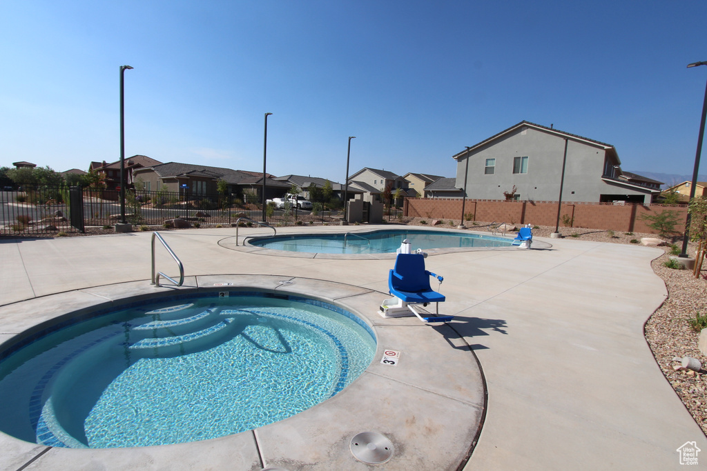 Community pool with a residential view, fence, a hot tub, and a patio area