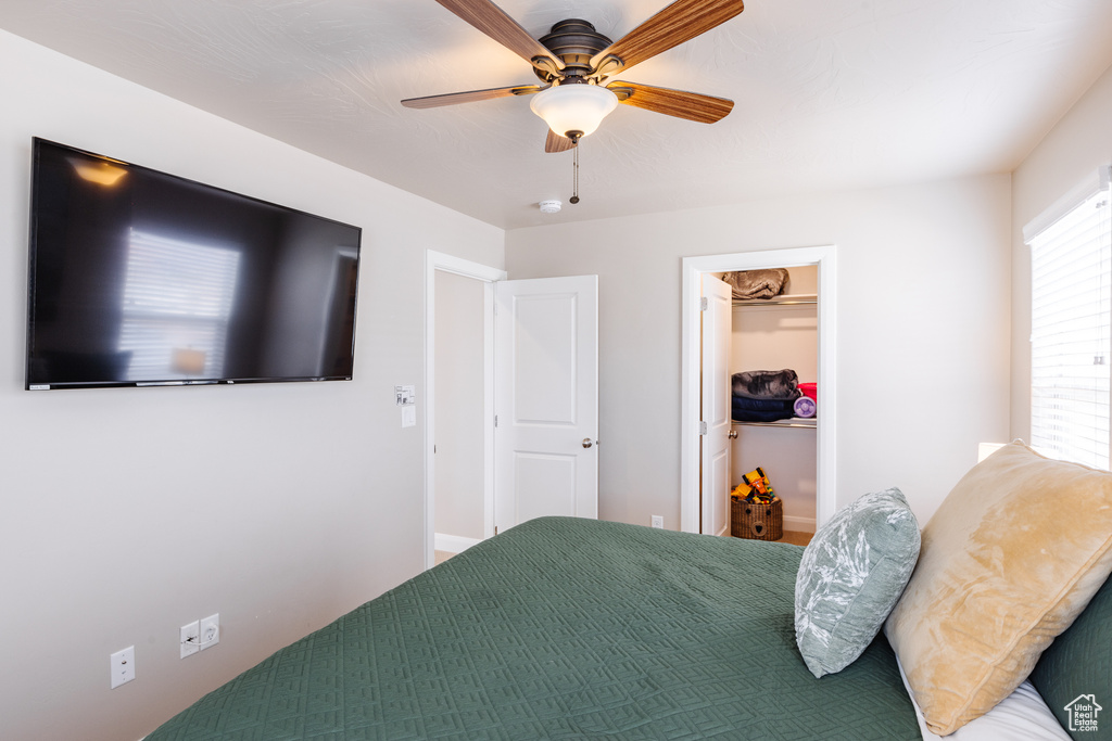 Bedroom with ceiling fan and a walk in closet