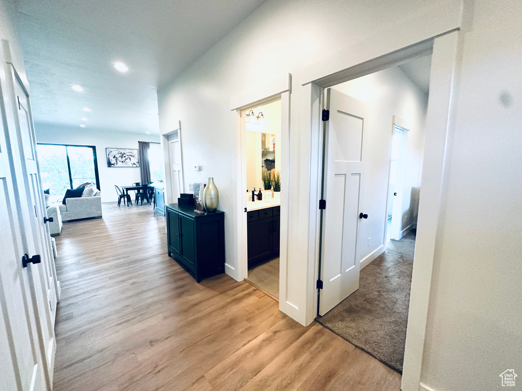 Hall with light wood finished floors, baseboards, and recessed lighting