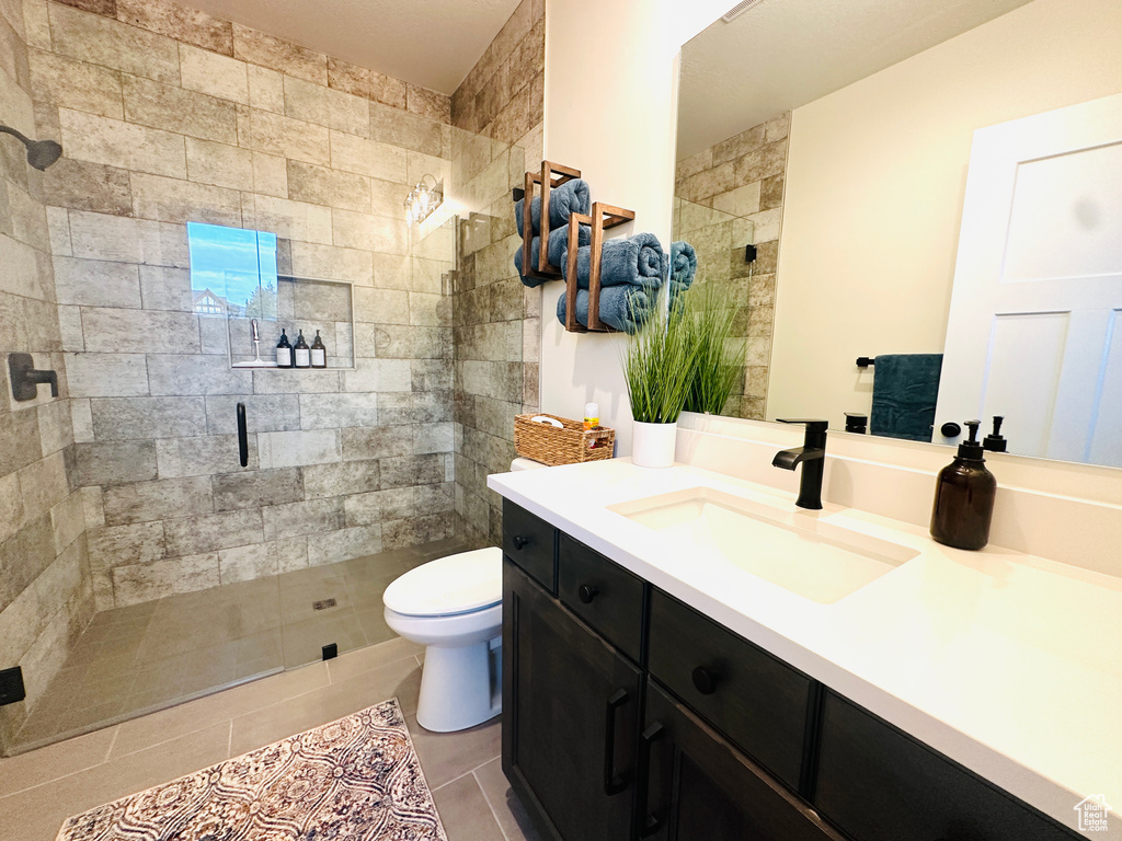 Bathroom featuring a shower stall, toilet, vanity, and tile patterned floors
