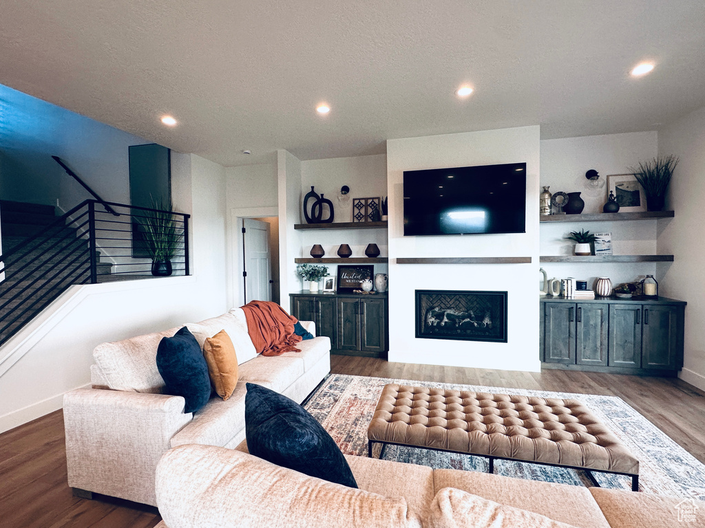 Living room with stairway, wood finished floors, a fireplace, recessed lighting, and baseboards