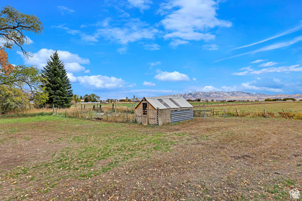 View of yard featuring a view of rural / pastoral area, an outbuilding, fence, a mountain view, and exterior structure