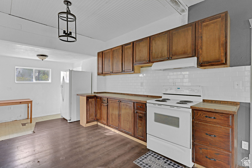 Kitchen featuring white appliances, under cabinet range hood, tasteful backsplash, and dark wood-style floors
