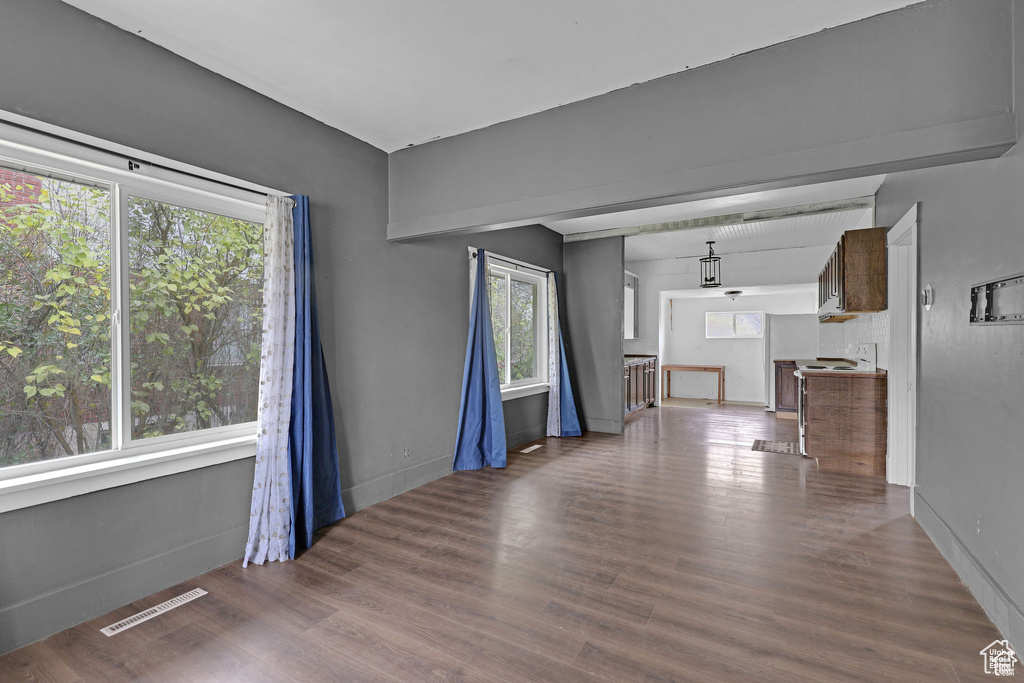 Unfurnished living room with healthy amount of natural light, baseboards, and wood finished floors
