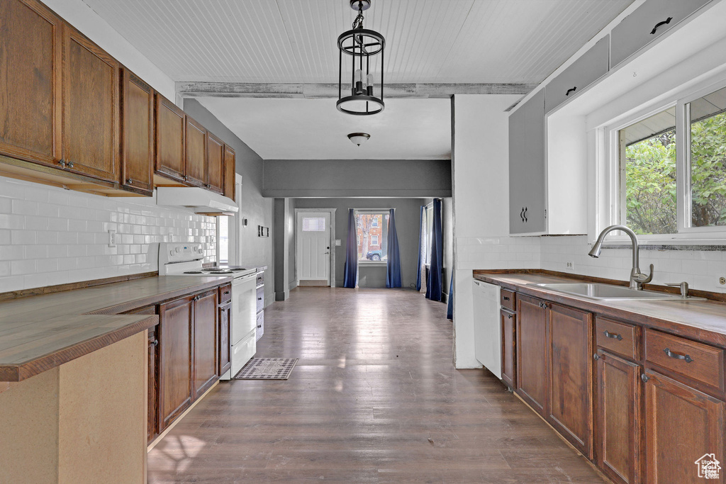 Kitchen with white appliances, a sink, under cabinet range hood, and decorative backsplash