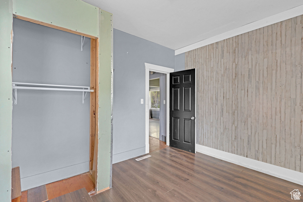 Unfurnished bedroom with wood finished floors, a closet, and baseboards