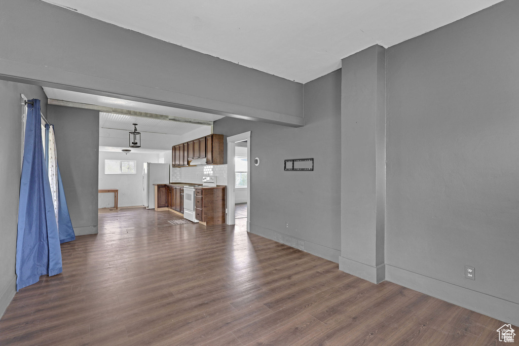 Unfurnished living room with dark wood-style floors and baseboards