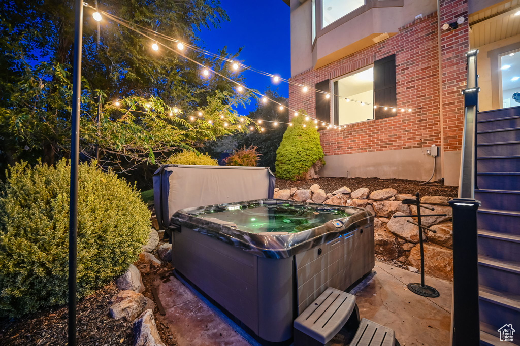 Patio at night featuring a hot tub