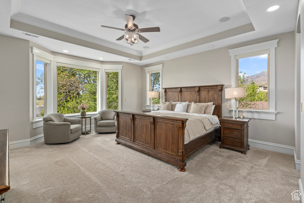 Bedroom with a tray ceiling, light carpet, ornamental molding, baseboards, and recessed lighting