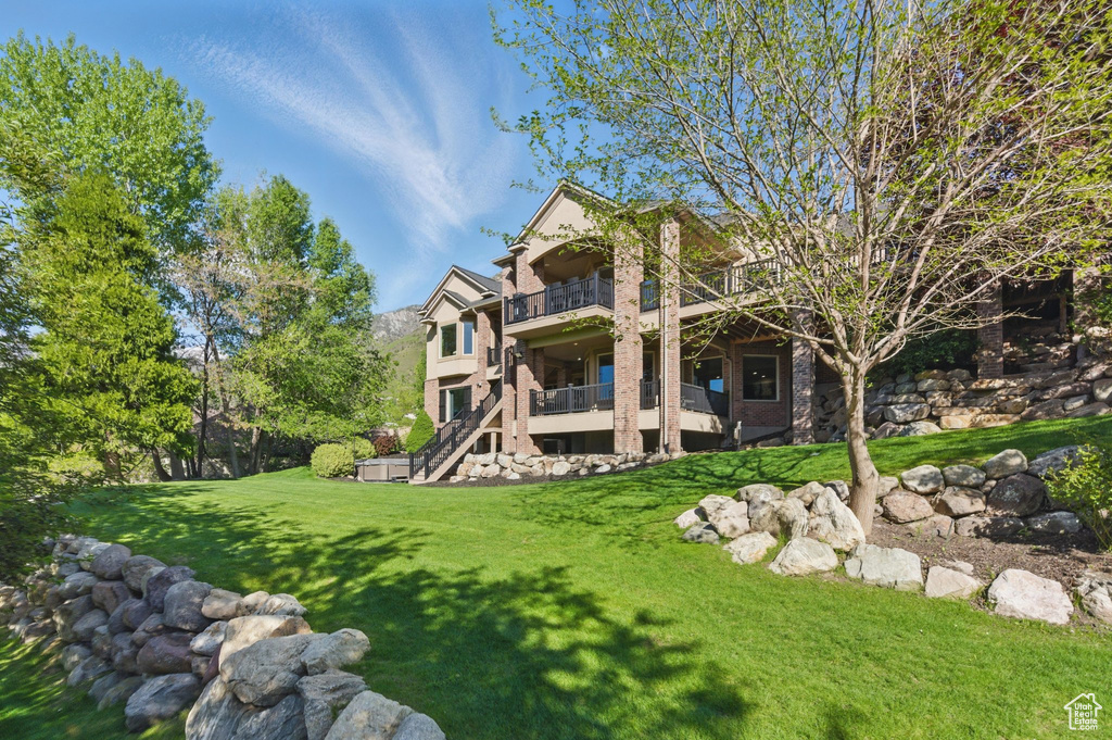 View of green lawn featuring a balcony and stairway
