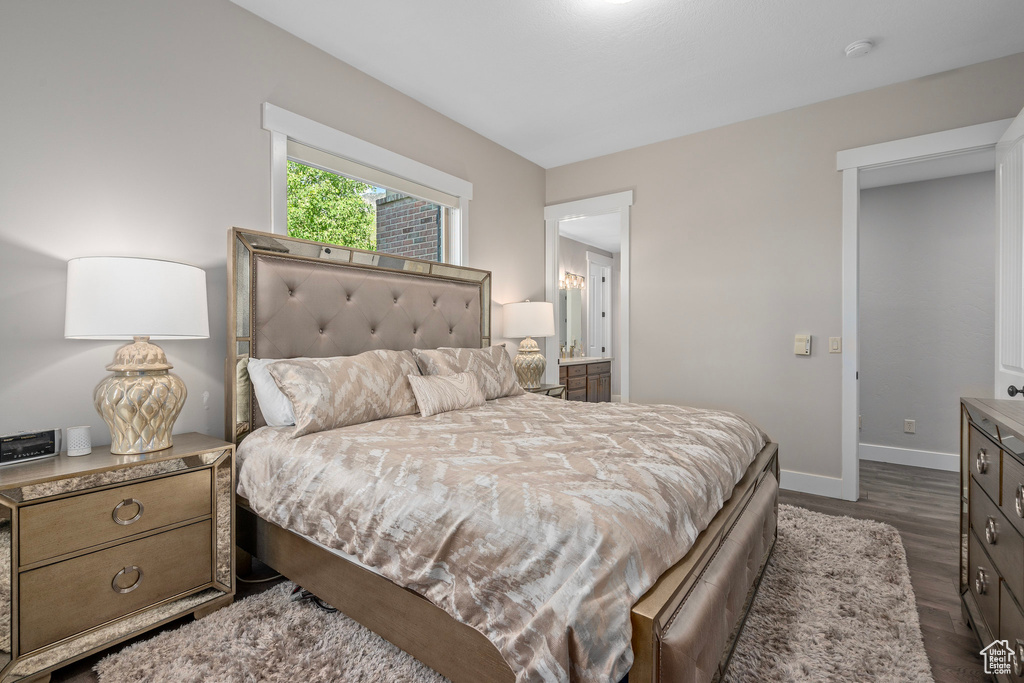 Bedroom featuring dark wood-style flooring, baseboards, and connected bathroom
