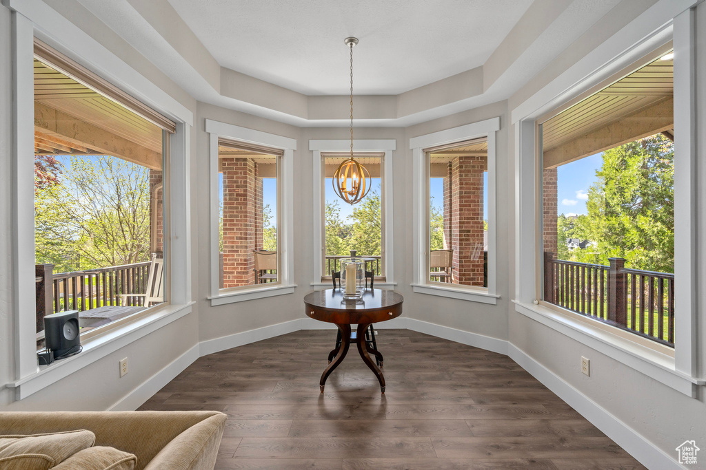 Sunroom / solarium featuring healthy amount of natural light, a chandelier, wood finished floors, and baseboards