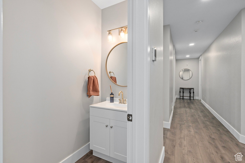 Bathroom featuring wood finished floors, baseboards, vanity, and recessed lighting