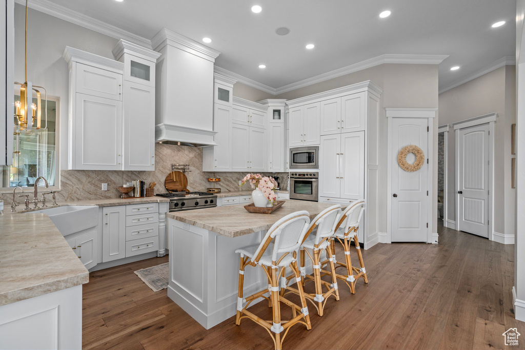 Kitchen featuring appliances with stainless steel finishes, white cabinets, crown molding, tasteful backsplash, and recessed lighting