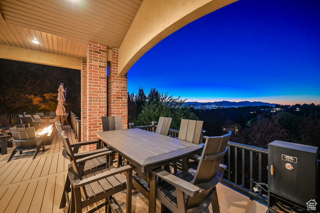 Deck at dusk featuring outdoor dining space and a mountain view