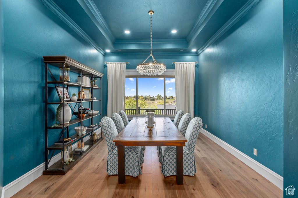 Office space with a raised ceiling, a chandelier, ornamental molding, wood finished floors, and a textured wall