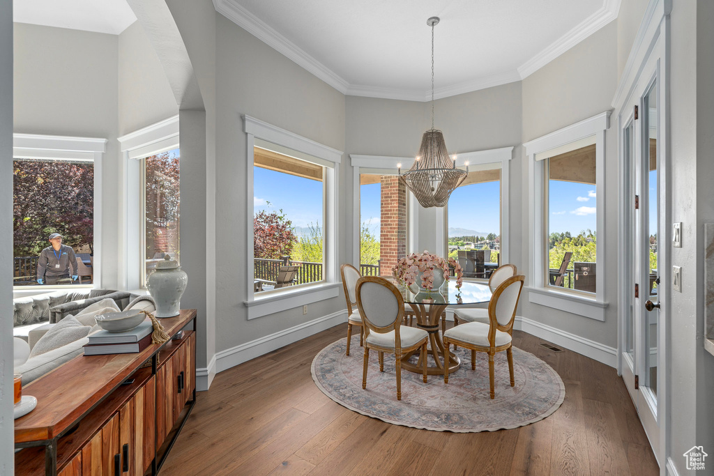 Dining room with a chandelier, baseboards, wood finished floors, and ornamental molding
