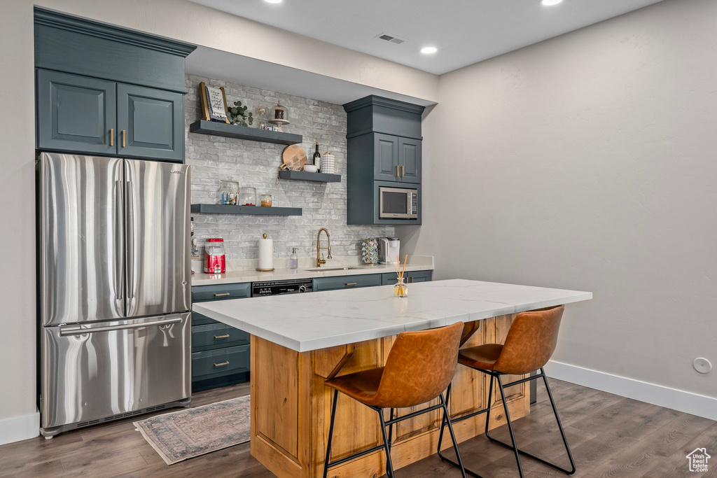 Indoor wet bar with stainless steel appliances, backsplash, baseboards, dark wood-type flooring, and recessed lighting
