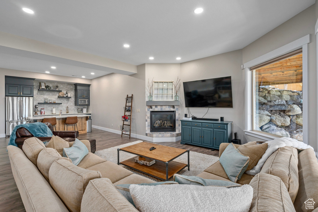Living area with wet bar, wood finished floors, recessed lighting, a glass covered fireplace, and baseboards