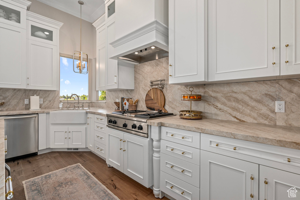 Kitchen featuring a sink, appliances with stainless steel finishes, white cabinets, light countertops, and ornamental molding
