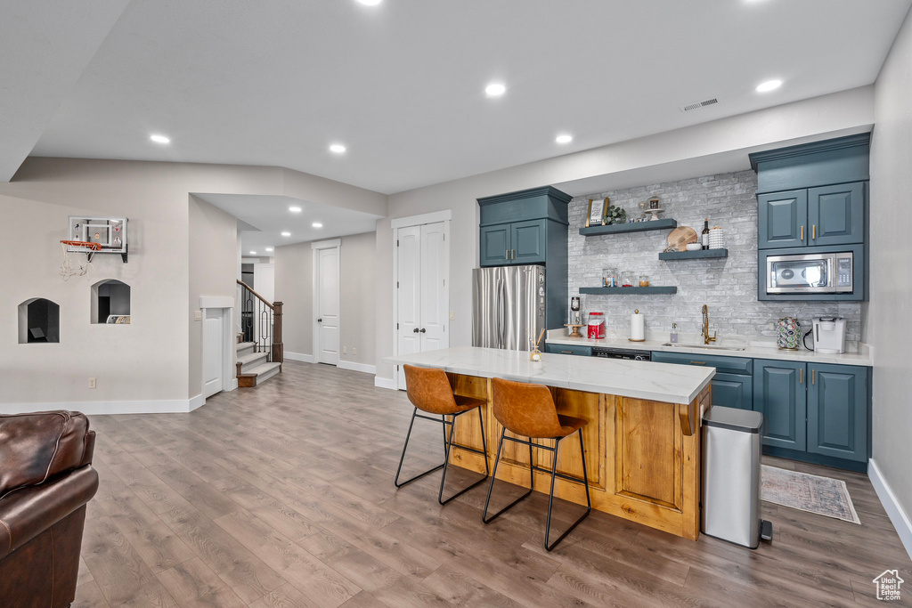Indoor wet bar with stainless steel appliances, stairs, wood finished floors, baseboards, and recessed lighting