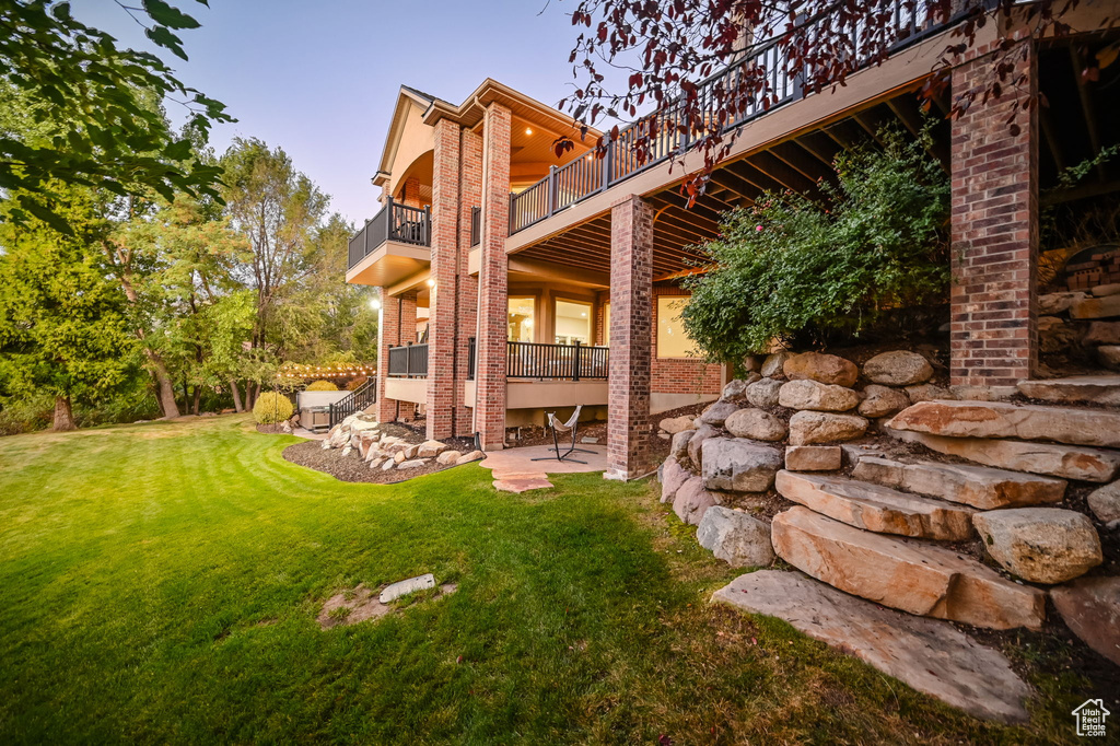 View of green lawn with a balcony and a patio area
