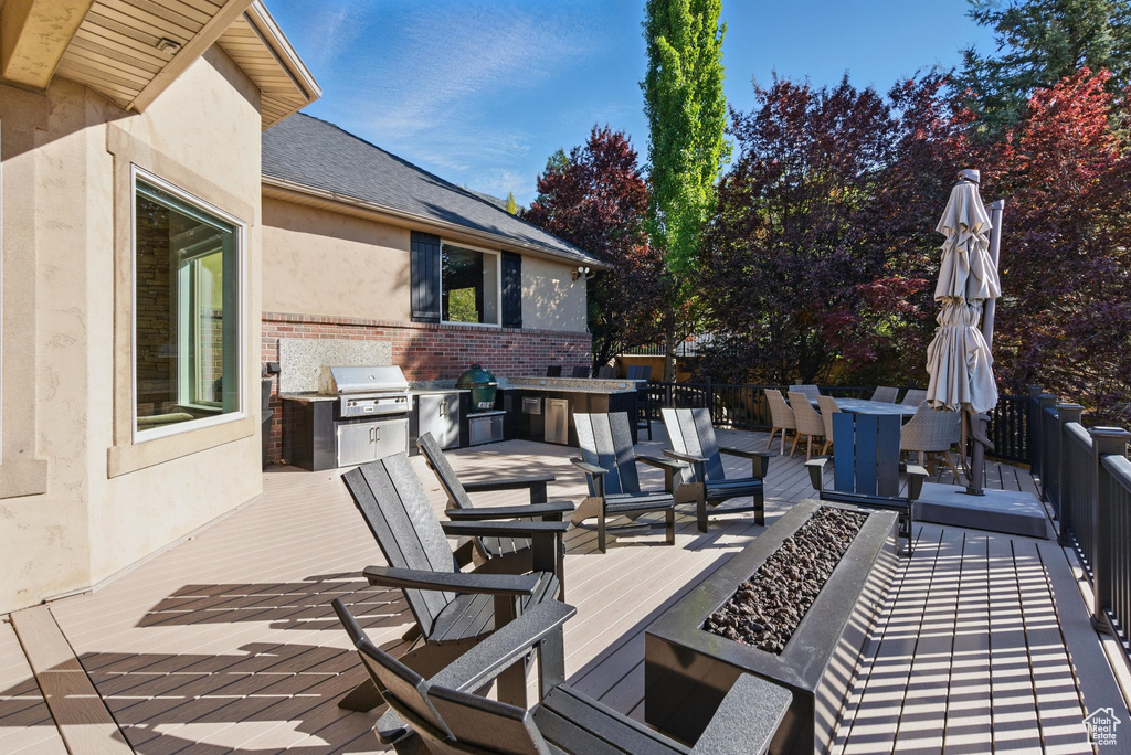 Deck with an outdoor fire pit, exterior kitchen, outdoor dining space, and area for grilling